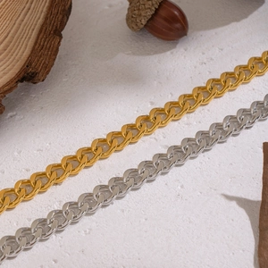 Detailed view of mixed gold and silver chunky Cuban link necklaces on a textured surface