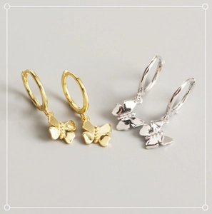 Close-up of gold and silver butterfly hoop earrings with polished metallic finish