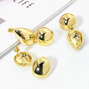 Detailed view of gold C-shaped earring set featuring teardrop and sphere stud designs