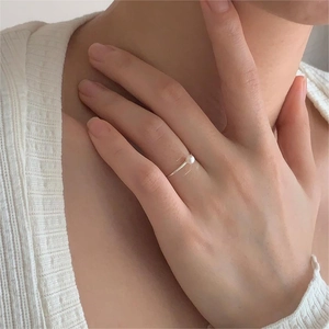 Close-up of minimalist S925 silver pearl ring worn on model hand with soft lighting