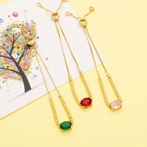 Detailed shot of three adjustable gold bracelets with green, red, and pink oval gemstones