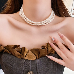 Nahaufnahme einer eleganten vierreihigen Perlenkette am Hals eines Models
