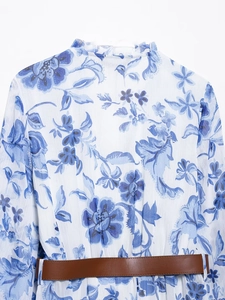 Detail of blue and white floral chiffon dress with ruffled collar and brown leather belt