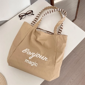 Detail of khaki canvas tote bag with Bonjour magic print and plush striped handles