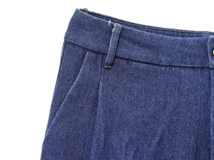 Dettaglio dei pantaloni in denim blu scuro con cuciture gialle e passanti per cintura