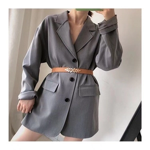 Detailed view of a brown leaf buckle belt cinched over a grey blazer for a stylish look