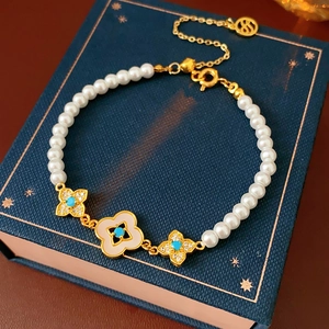 Dettaglio di un bracciale floreale placcato oro 18k con perle e turchese su scatola regalo