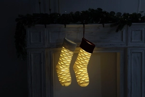 Macro shot of white knitted Christmas stockings with LED lights on a green fireplace mantel