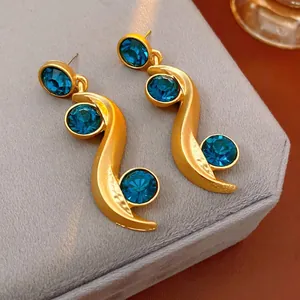 Vintage gold wavy earrings with dark blue crystals displayed on a velvet jewelry box
