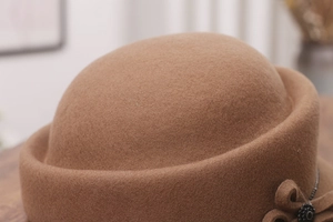 Macro shot of brown wool felt equestrian hat with a chic bow and vintage bead detail