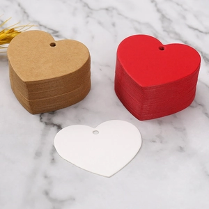 Macro shot of heart-shaped kraft paper tags in brown, red, and white on marble surface
