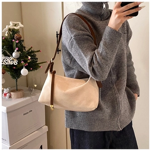 Detail of beige suede crescent bag with dark brown leather strap and golden buckles
