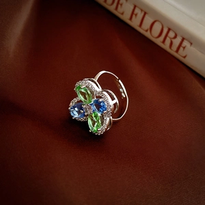 Macro shot of silver flower ring with marquise-cut green and blue crystals on silk