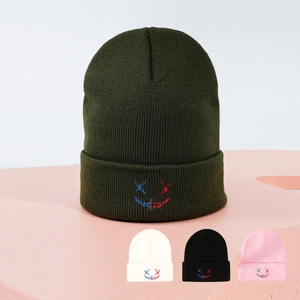 Détail de la broderie visage fantôme bicolore sur le bonnet en tricot vert foncé