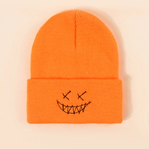 Bright orange knit beanie featuring a black embroidered devil face on a plain background