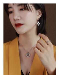 Close-up of silver irregular pendant necklace, cross earrings and ring set on a model