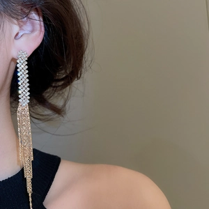 Close-up of elegant gold tassel earrings with rhinestones on model's ear