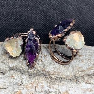 Macro shot of copper wire-wrapped rings featuring raw purple amethyst and green crystals