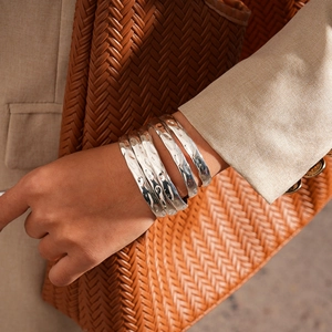 Gros plan de bracelets joncs argentés empilés avec texture martelée au poignet