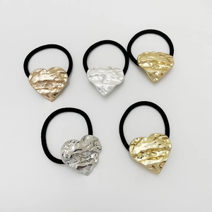 Close-up of black elastic hair ties featuring gold and silver textured heart charms