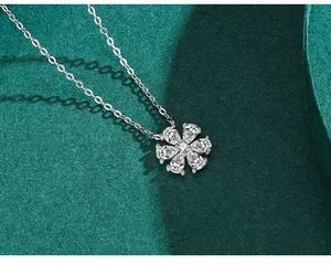 Detailed close-up of a silver floral pendant with white zircon on green velvet background