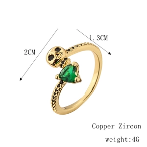 Detail of gold skull ring with green heart zircon and black pavé stones on a white background