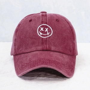 Close-up of white face embroidery on vintage washed burgundy cotton baseball cap