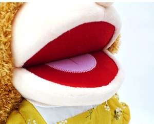 Detailed close-up of a plush monkey hand puppet's open mouth and floral dress pattern
