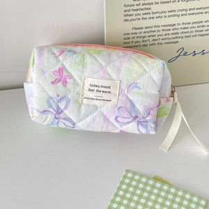 Detailed close-up of quilted floral makeup bag with macaron tones and zipper detail