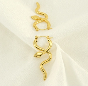Close-up of gold-plated snake earrings with snap closure on beige linen fabric