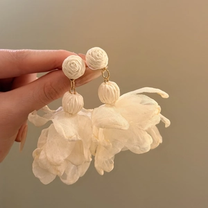 Handmade raffia studs with ivory chiffon flower tassels shown in close-up detail