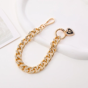 Golden Cuban link chain strap with iced-out rhinestone heart pendant and black bow detail