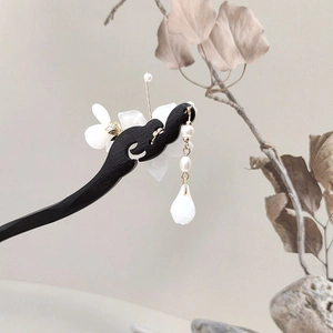 Detail of elegant wooden hair pin featuring white magnolia flower and pearl tassels