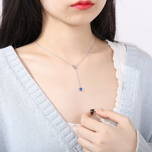 Detail of silver Y-shaped necklace featuring a hollow heart link and blue heart pendant