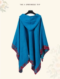 Detail view of ethnic blue knit hooded poncho with colorful geometric hem pattern