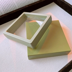 Detail of matcha green floating jewelry case with clear PE film on a minimal background