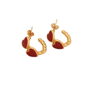 Golden C-shaped stainless steel earrings with red heart charms on a white background