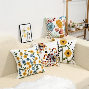 Set of four floral embroidered cotton linen cushion covers on a modern beige sofa