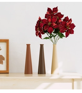 Three conical ceramic vases in brown and beige with festive red poinsettia flowers