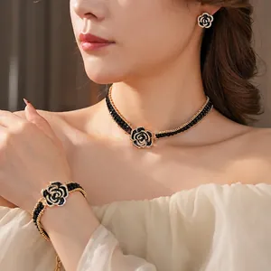 Elegant gold jewelry set with black rose pendants and pavé crystals on a woman