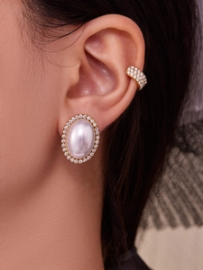 Detailed macro view of 18k gold plated pearl studs and zircon cuff worn by a model