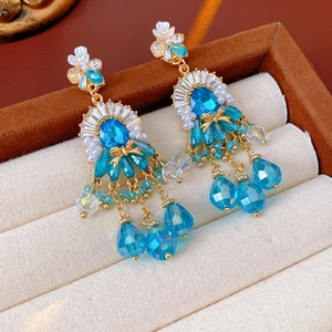Macro di orecchini vintage dorati con cristalli blu e perle in una scatola per gioielli