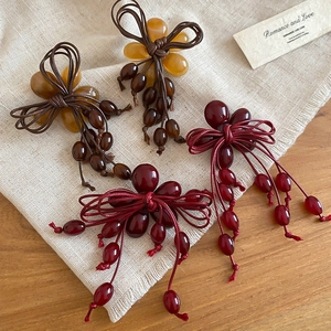 Detail of handmade resin flower tassels with amber and burgundy beaded weave jewelry