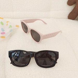 Detail of pink and black kids sunglasses with rivet accents on white fleece background