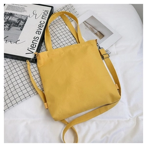Top view of a yellow canvas tote bag with adjustable strap and dark metal hardware
