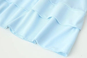 Close-up of light blue fabric featuring layered ruffle edges and fine texture detail