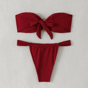 Flat lay of wine red bandeau bikini set featuring a front bow and gold ring detail