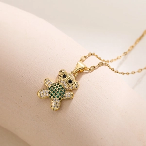 Macro shot of bear pendant with green and white zircons on a delicate gold chain necklace