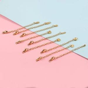Golden stainless steel extension chains with lobster clasps and S.STEEL tags on bicolor background