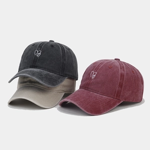 Detailed shot of three washed cotton baseball caps with embroidered heart designs